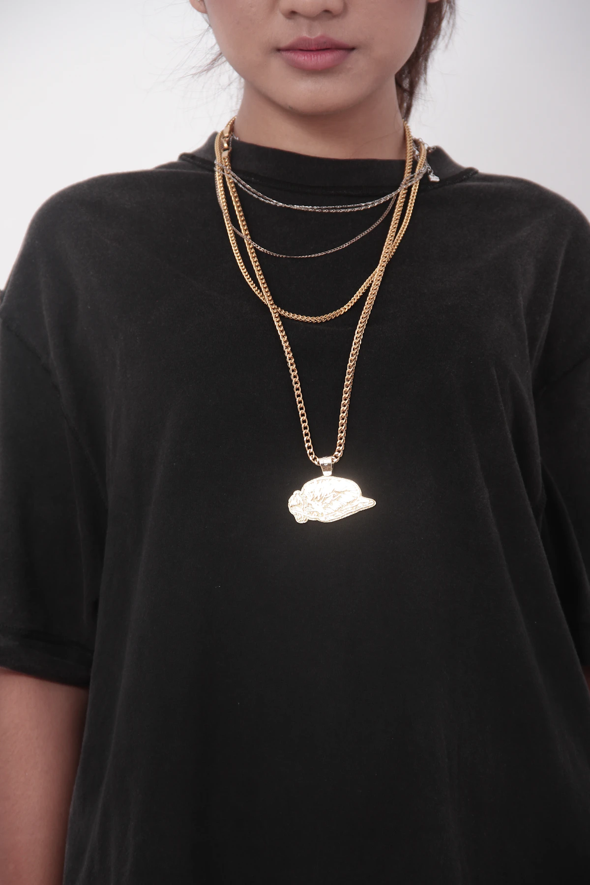 Person wearing layered gold necklaces with a pendant